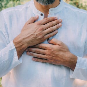Man holding chest with both hands gently