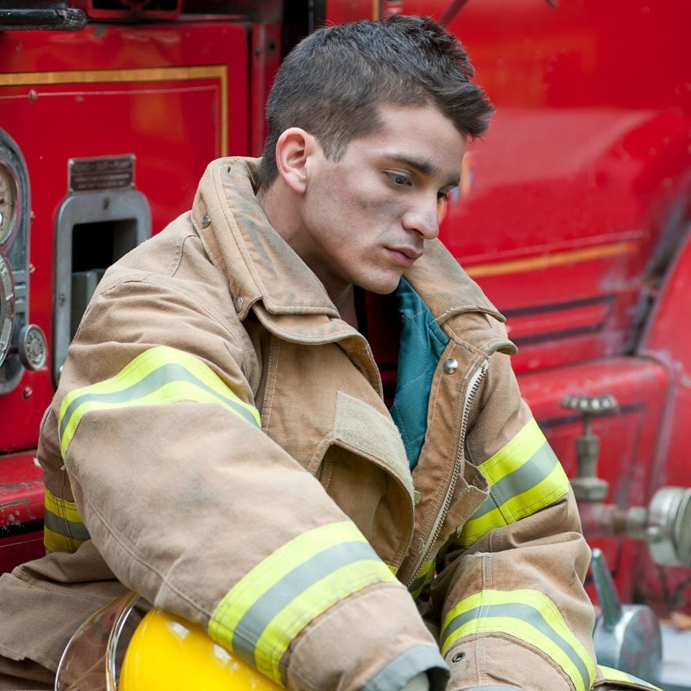 Firefighter sitting in gear, looking emotionally distressed