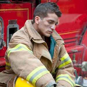 Firefighter sitting in gear, looking emotionally distressed