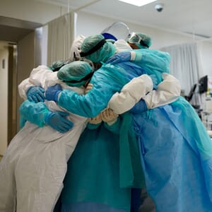Medical team in full PPE sharing group hug
