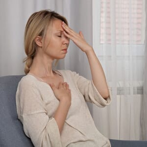 Woman practicing mindfulness with hand on forehead