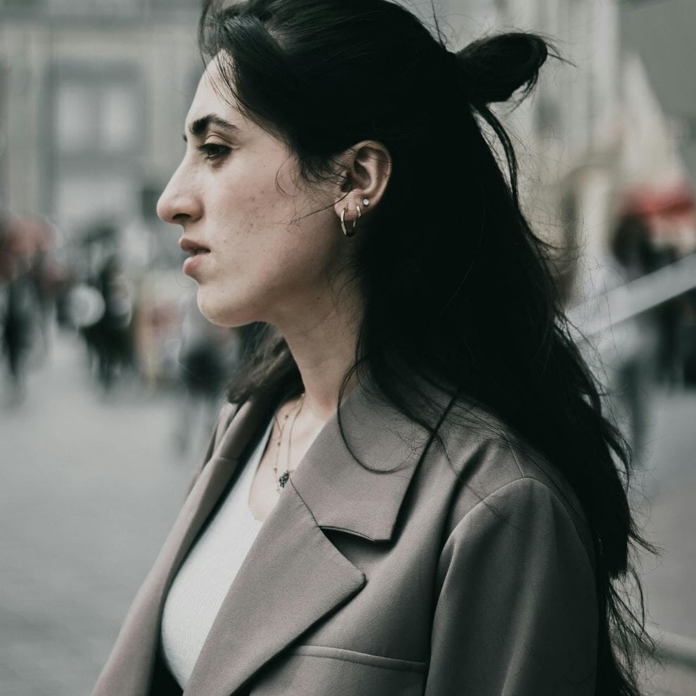 Woman looking tense and distant while standing outdoors.